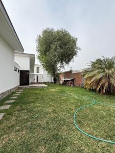 a yard with a hose laying on the grass at Casa los Cipreses del Sol in Cieneguilla
