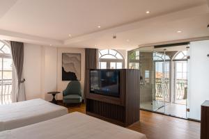 a bedroom with two beds and a flat screen tv at Devesun Boutique Hotel Phú Quốc in Phú Quốc