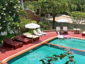 a swimming pool with chairs and umbrellas next to at Lanna Oriental Maejo in Chiang Mai
