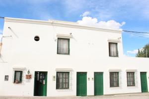 a white building with green doors on a street at Hostal Las Tinajas de Cachi in Cachí