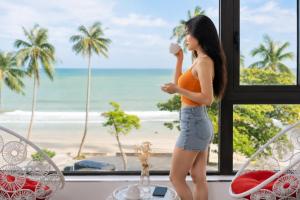 a woman standing in front of a window with a view of the beach at Sontra Sea Hotel in Danang