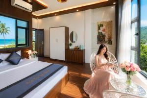 a woman sitting in a chair in a bedroom at Sontra Sea Hotel in Danang
