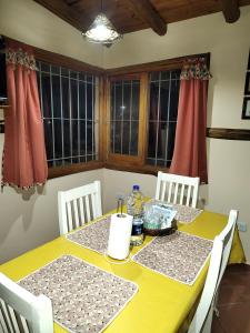 a yellow table with two chairs and two windows at Cabañas Mónika III Norte in Huerta Grande +49 photos