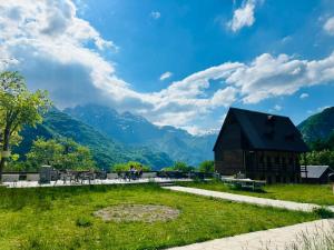 a barn in a field with mountains in the background at Guesthouse Gjoni Theth in Theth