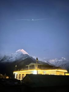 a building with snow covered mountains in the background at Sunshine lodge in Namche