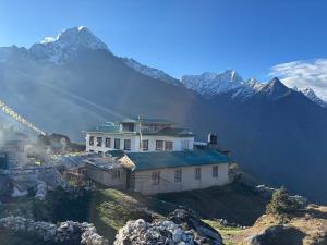 a house on a hill with a mountain in the background at Sunshine lodge in Namche