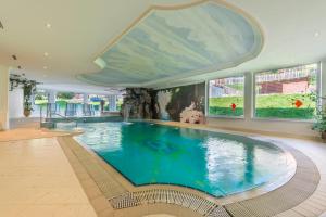 - une grande piscine dans un bâtiment doté d'un grand plafond dans l'établissement Alpino Charme Apartments, à Peio