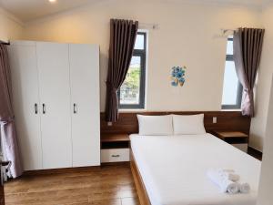 a bedroom with a large white bed and cabinets at Carol Dalat in Khu Chi Lăng