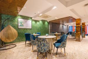 a restaurant with tables and chairs and a green wall at Treebo Noida Business Suites in Okhla