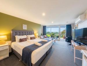 a large bedroom with a large bed and a flat screen tv at The Sandridge Motel in Lorne