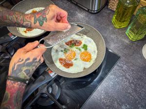 a person cooking eggs in a pan on a stove at De Zilte Zeehoeve in Ellemeet