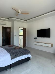 a bedroom with a bed and a flat screen tv at Villa Fiesta, 5bd, palace in Mae Nam