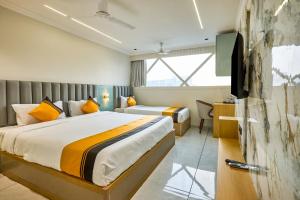 a hotel room with two beds and a television at Itsy Hotels Grand CG in Ahmedabad +34 photos