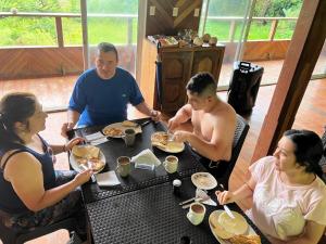 a group of people sitting around a table eating food at Villa Encanto in Bahía Solano