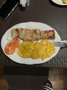 a plate of food with eggs and meat and tomatoes at Villa Encanto in Bahía Solano