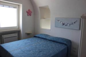 um quarto com uma cama com uma colcha azul e uma janela em La Torre em Ravello
