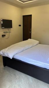 a bedroom with two beds and a flat screen tv at DownTown INN in Manendragarh