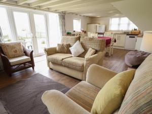 a living room with two couches and a kitchen at Shepherd's Cottage in Alford