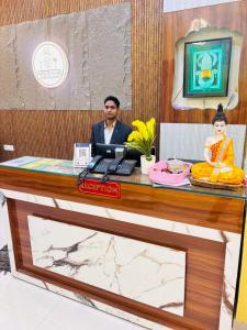 a man sitting at a desk with a laptop at Hotel gl palace & restaurant chomu in Jaipur