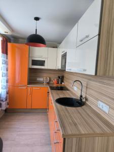 a kitchen with orange and white cabinets and a sink at Family Apartament in Narva-Jõesuu