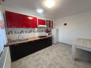 a kitchen with red cabinets and a white refrigerator at Apartaments Doriana in Vama Veche +34 photos