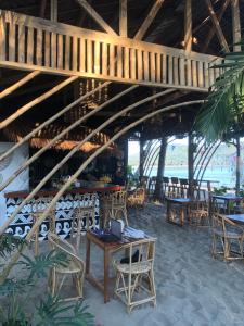 a restaurant on the beach with tables and chairs at Kubotique Beachfront Staycation in El Nido