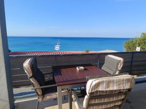 a table and chairs on a balcony overlooking the ocean at Jason Rooms & Studios in Keratokampos