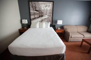 a hotel room with a large bed and a couch at Super 8 by Wyndham Whitecourt in Whitecourt +20 photos