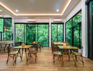 a restaurant with tables and chairs and large windows at Plerntaan HoReCa in Ban Khlong Kum