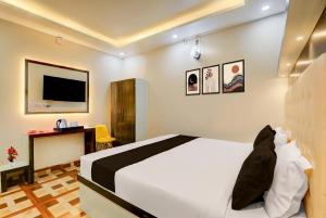 a bedroom with a bed and a desk and a tv at Collection O Jagdeo Path Patna in Patna