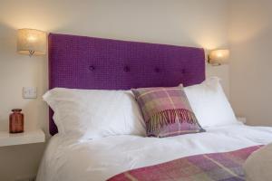 a bed with a purple headboard and two pillows at The Wee Thistle in Edinburgh