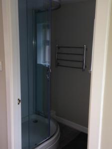 a glass shower in a bathroom with a toilet at Woodside Cottage Self Catering in Kinbuck
