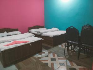 two beds in a room with pink and blue walls at Hotel crunchy shadowbegnas in Deorāli