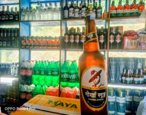 a bottle of beer sitting in front of a refrigerator at Hotel crunchy shadowbegnas in Deorāli