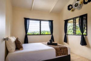 a bedroom with a bed and two windows at Hidden Haven - Group Retreat-Sleeps 7 aircon & free Wifi in Rarotonga