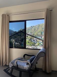 a room with a chair and a large window at Ashirwad Homestay in Bhowāli