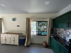 a kitchen with green cabinets and a window at Ashirwad Homestay in Bhowāli +8 photos
