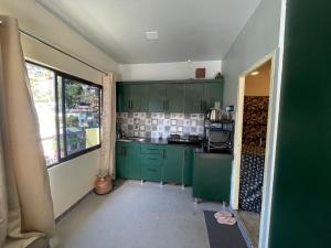 a kitchen with green cabinets and a large window at Ashirwad Homestay in Bhowāli