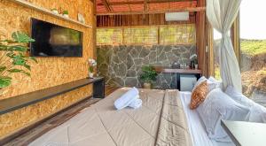a room with a couch and a tv on a wall at Salty Cabin Sunset Views Yeh Leh Beach in Balian