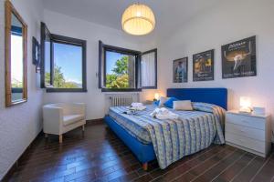 a bedroom with a blue bed and a chair and windows at La Parusciola Pool Residence in Gignese