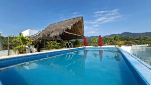 a swimming pool at a resort with a thatch roof at Villas Boutique Casa Ricarda in Aticama +24 photos