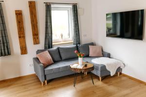a living room with a gray couch and a table at Ferienwohnung Enzian in Halblech