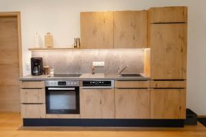a kitchen with wooden cabinets and a stove and sink at Ferienwohnung Enzian in Halblech
