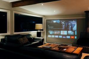 a living room with a couch and a large screen television at Stylish 2-Bed Home, Stunning View, Fire Pit, Festoon Lights, BBQ and walk to Pub in Poowong