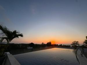 a swimming pool with a sunset in the background at Villas Boutique Casa Ricarda in Aticama