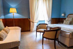 a bedroom with a bed and a chair and a couch at Grand Hotel Bastiani in Grosseto