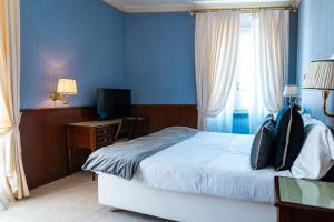 a bedroom with blue walls and a bed and a television at Grand Hotel Bastiani in Grosseto