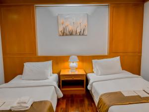 a room with two beds and a table with a picture at Lanna Oriental Maejo in Chiang Mai