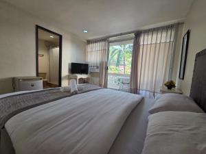 a bedroom with a large white bed with a window at Hotel Bella Monte in Olongapo