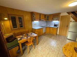 a kitchen with wooden cabinets and a table and a refrigerator at Chata u Vachtů in Kubova Huť